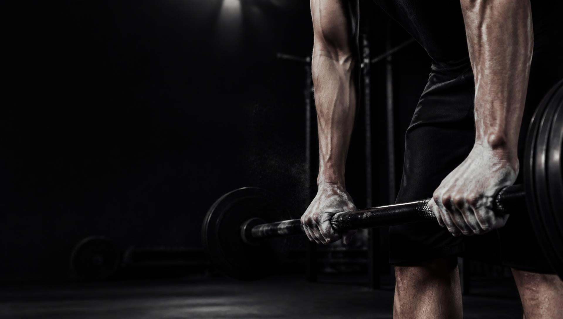 Lifter gripping a loaded barbell with chalked hands